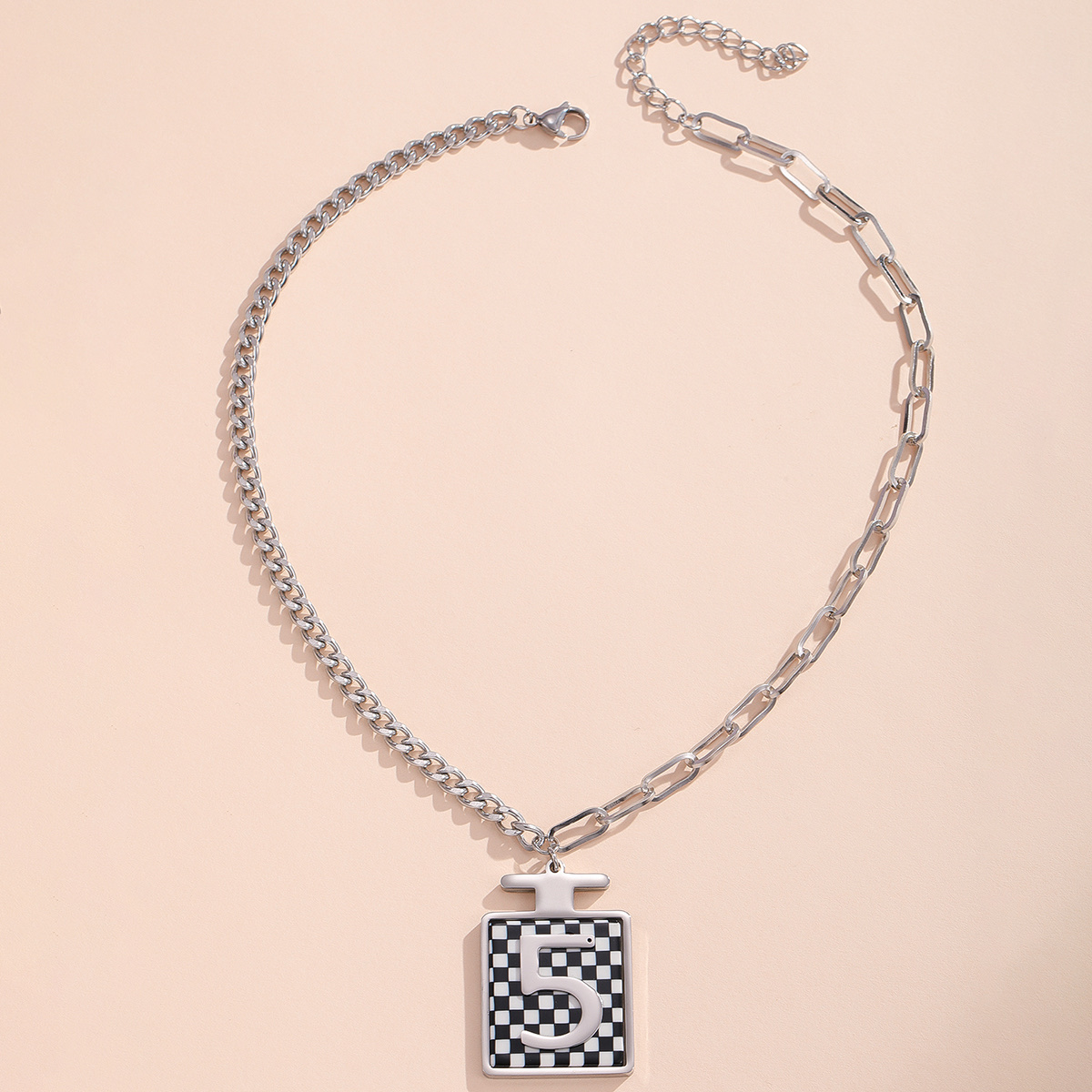 A black and white B-shaped stainless steel necklace in a perfume bottle