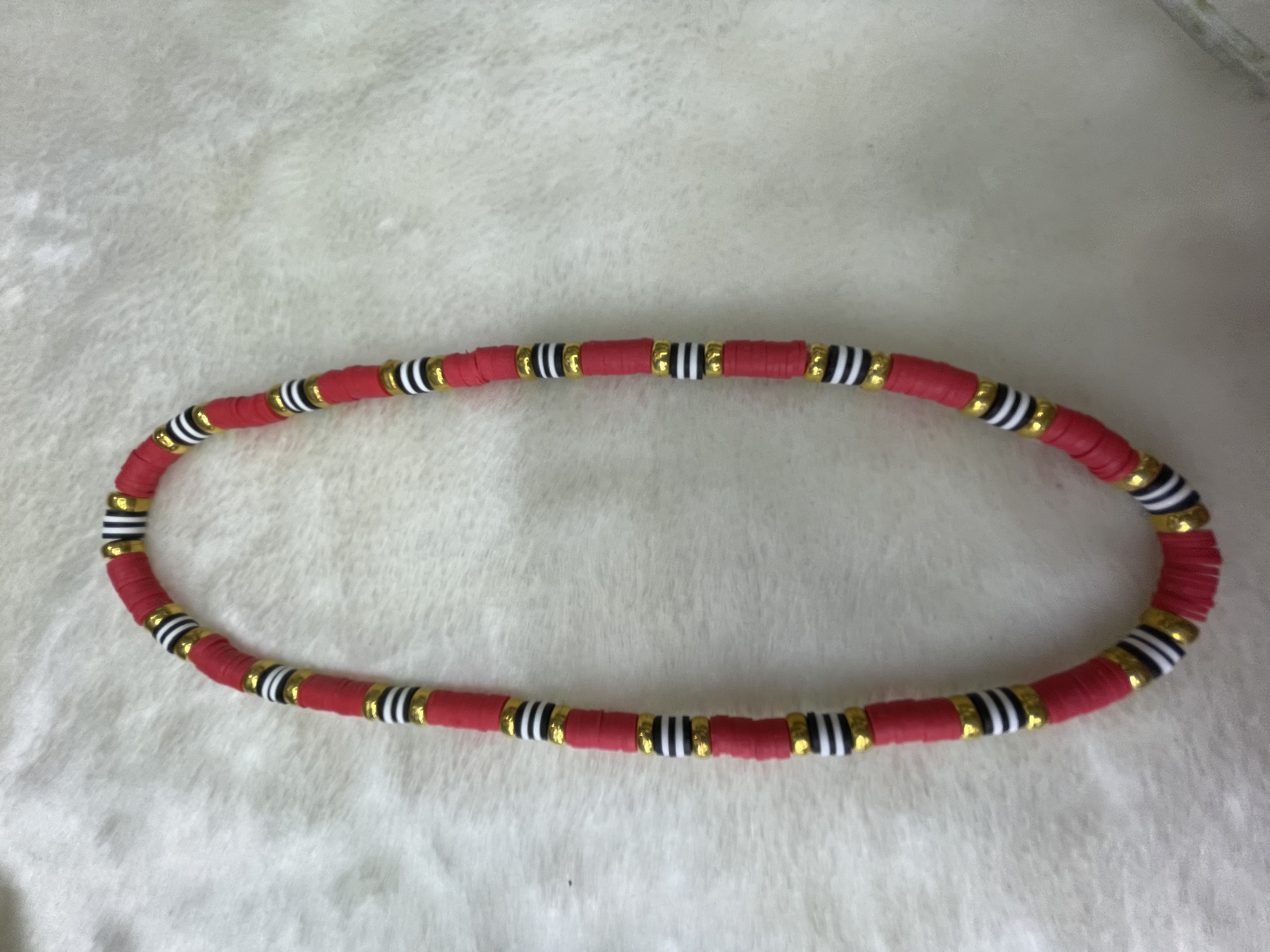 A necklace of large red soft clay shards and gilded flat beads details Picture
