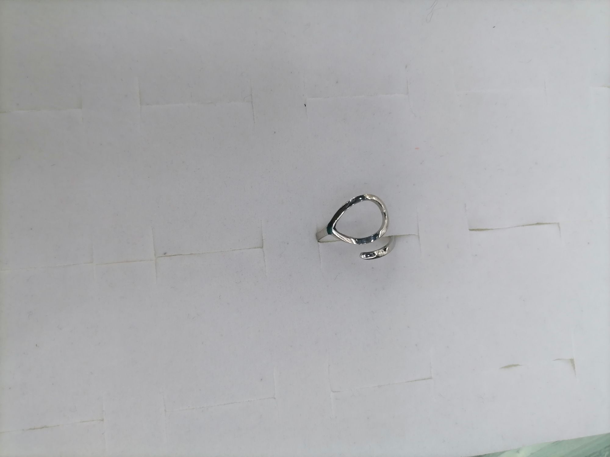 A titanium steel silver ring with a hollowed-out oval on top and a line at the bottom