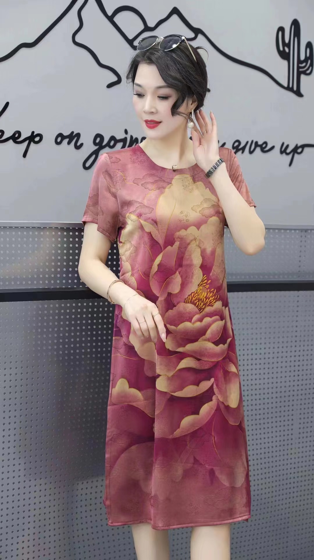 This is a new 2023 faux silk No. 7 dress with a round neck and short sleeves. It is a casual summer dress for the middle-aged and elderly, fashionable and comfortable. It is in a dark purple-red color and suitable for home, travel, and meeting friends. It is a large-sized loose dress.