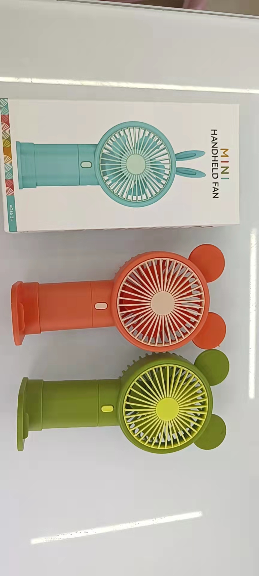 The 933-131 cartoon handheld phone stand fan comes in three colors: blue, green and orange, making it convenient to carry