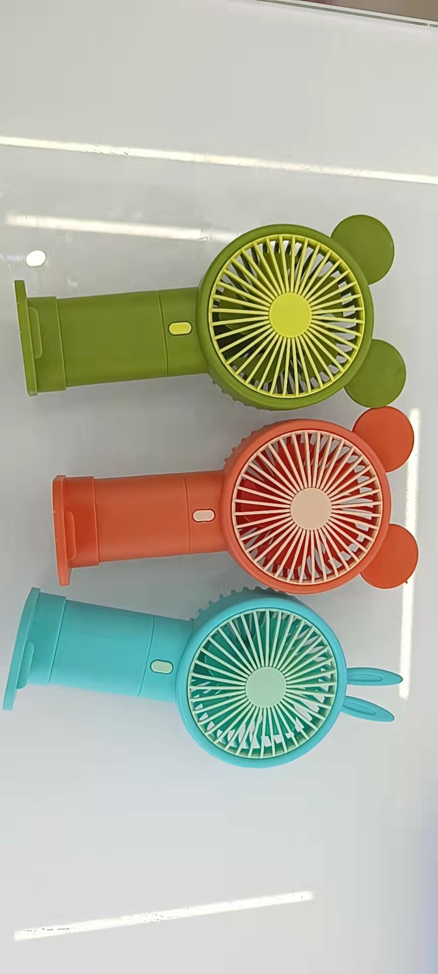 The 933-131 cartoon handheld phone stand fan comes in three colors: blue, green and orange, making it convenient to carry Item Picture