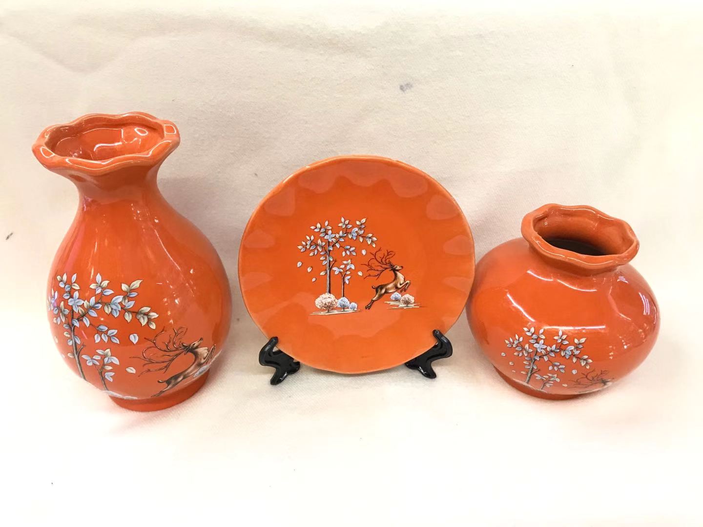 An orange three-piece set of plates + vase
