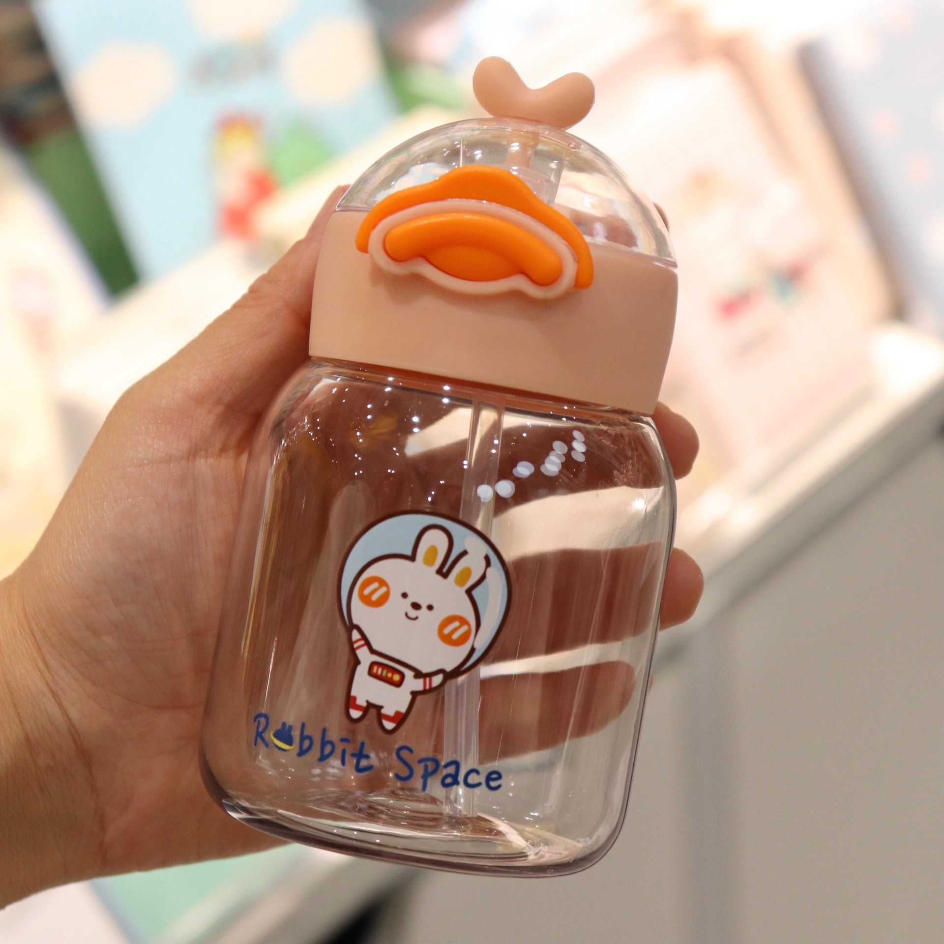 A creative and cute cartoon hand-held plastic cup with a straw